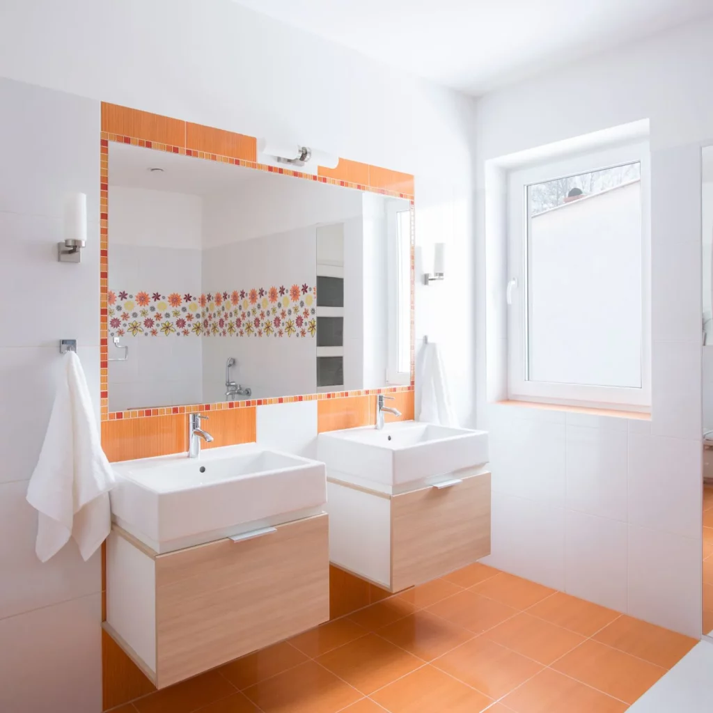 White bathroom with orange and wood accents - cover image for bathroom essentials for first apartment post