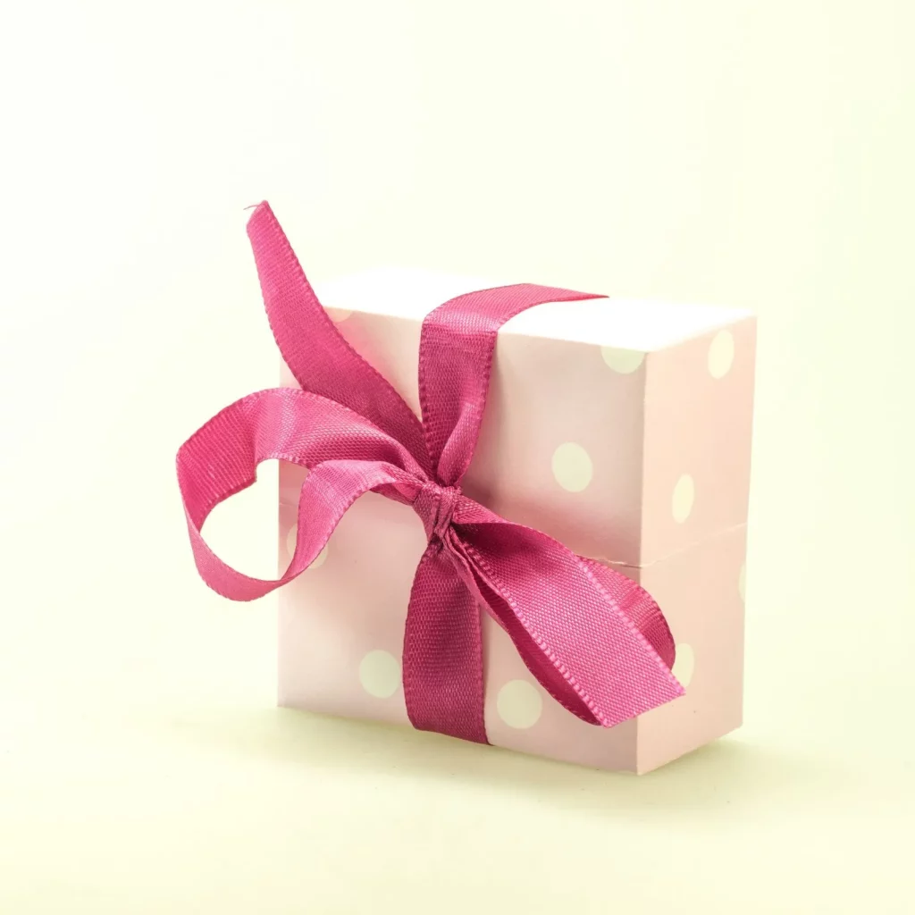 A pink and white polka dot gift box tied with pink ribbon - cover image for roommate gift ideas blog post