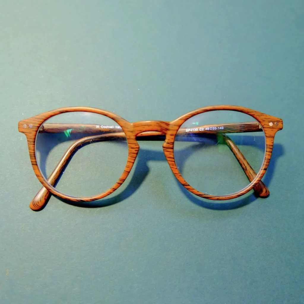 Cover image for how to save money on glasses post - features a pair of glasses in the middle of a blue table